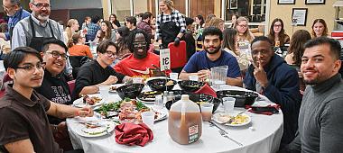 Seven friends pose seated at the table as they wrap up their dinner.